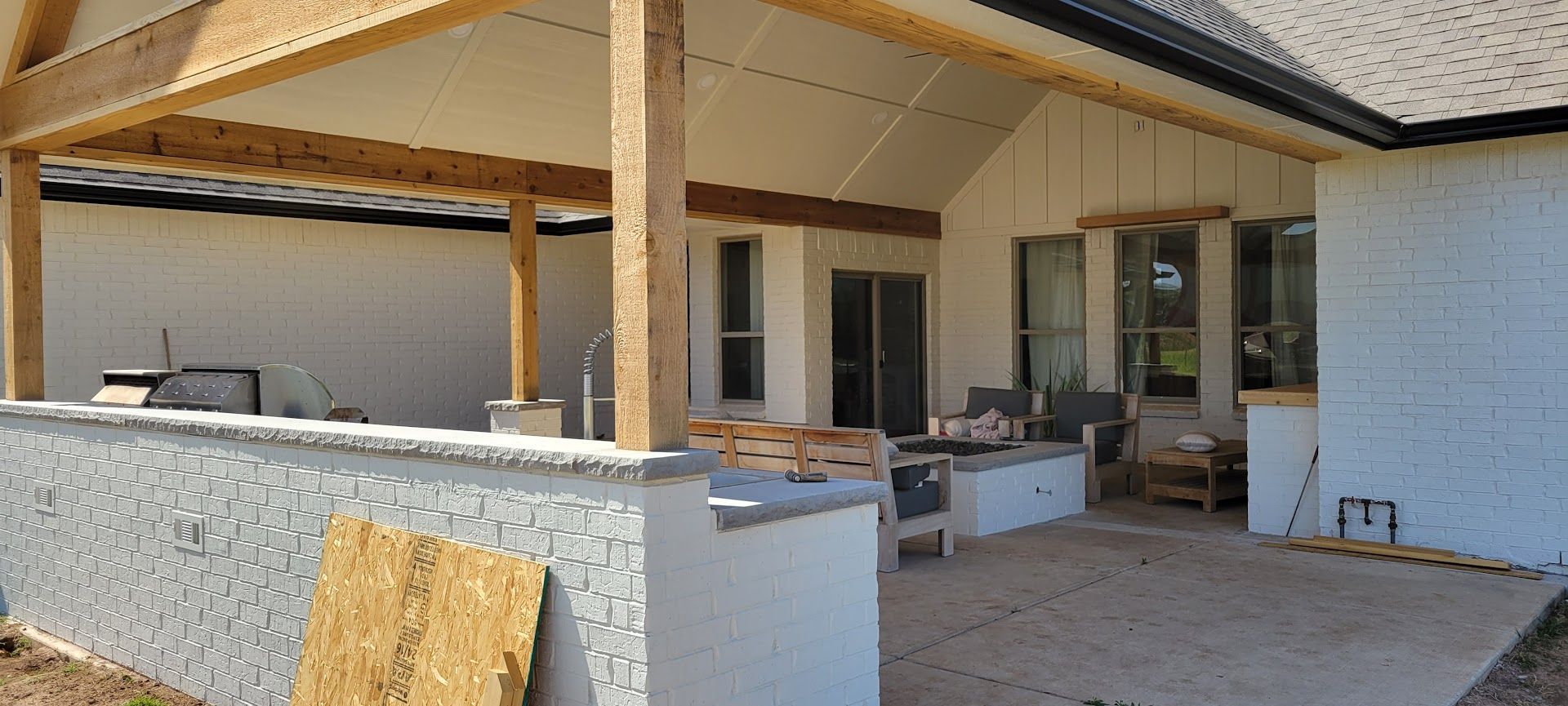 Partially built patio with wood posts, white brick walls, and construction materials in front