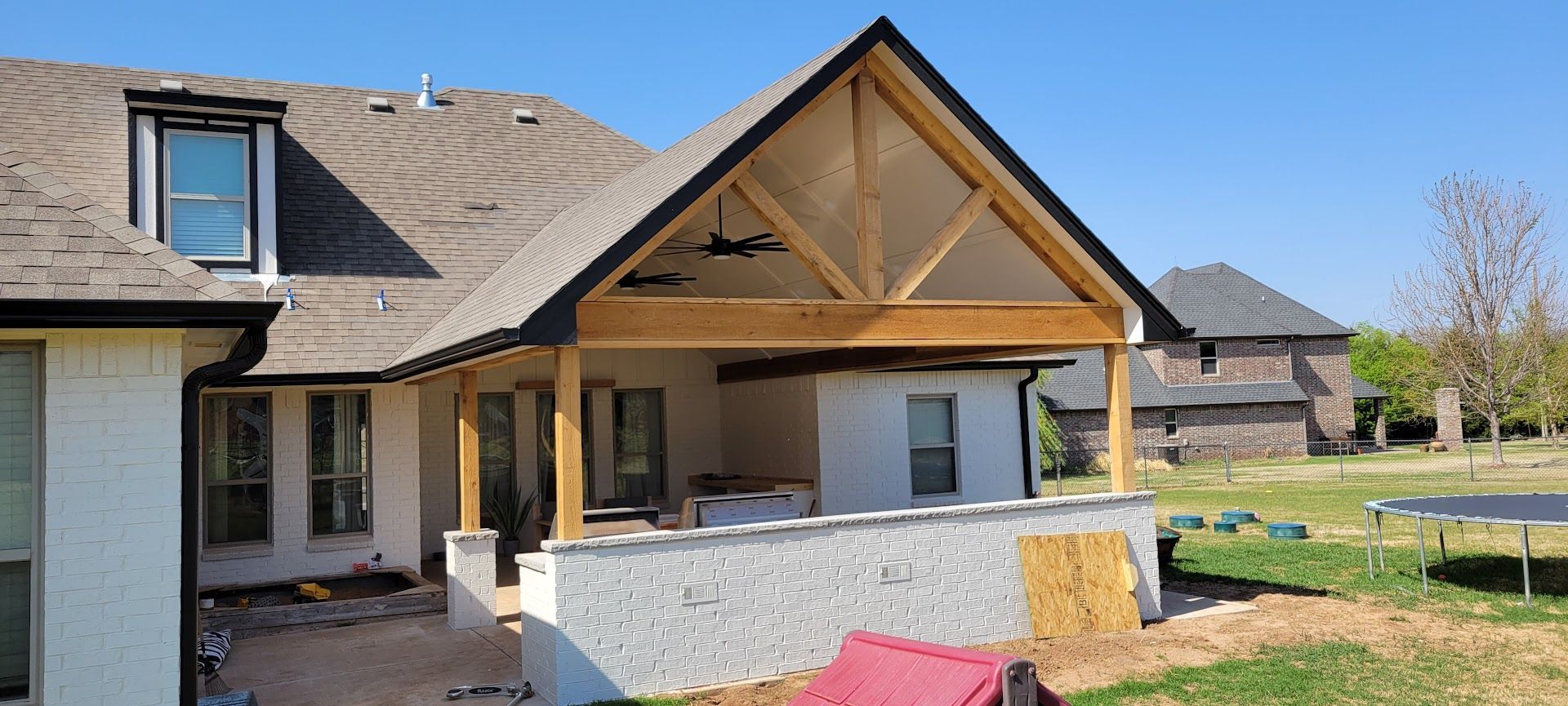 Backyard patio with stone house, wooden gabled roof, and partial outdoor seating area