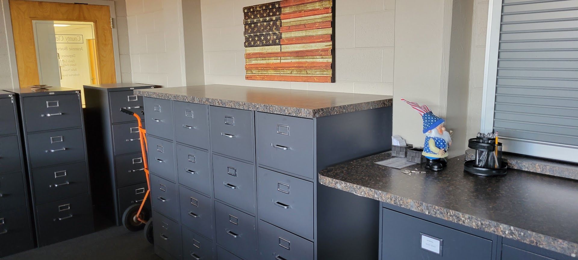 Office break room with gray cabinets, countertops, and an American flag on the wall.