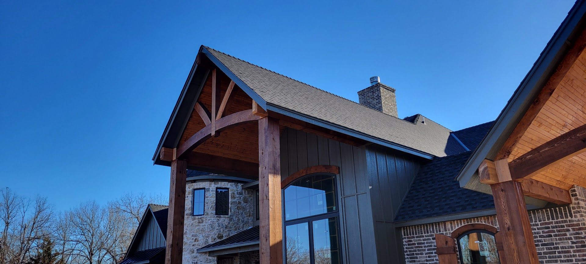 Brick house with gabled roof and large windows against a clear blue sky
