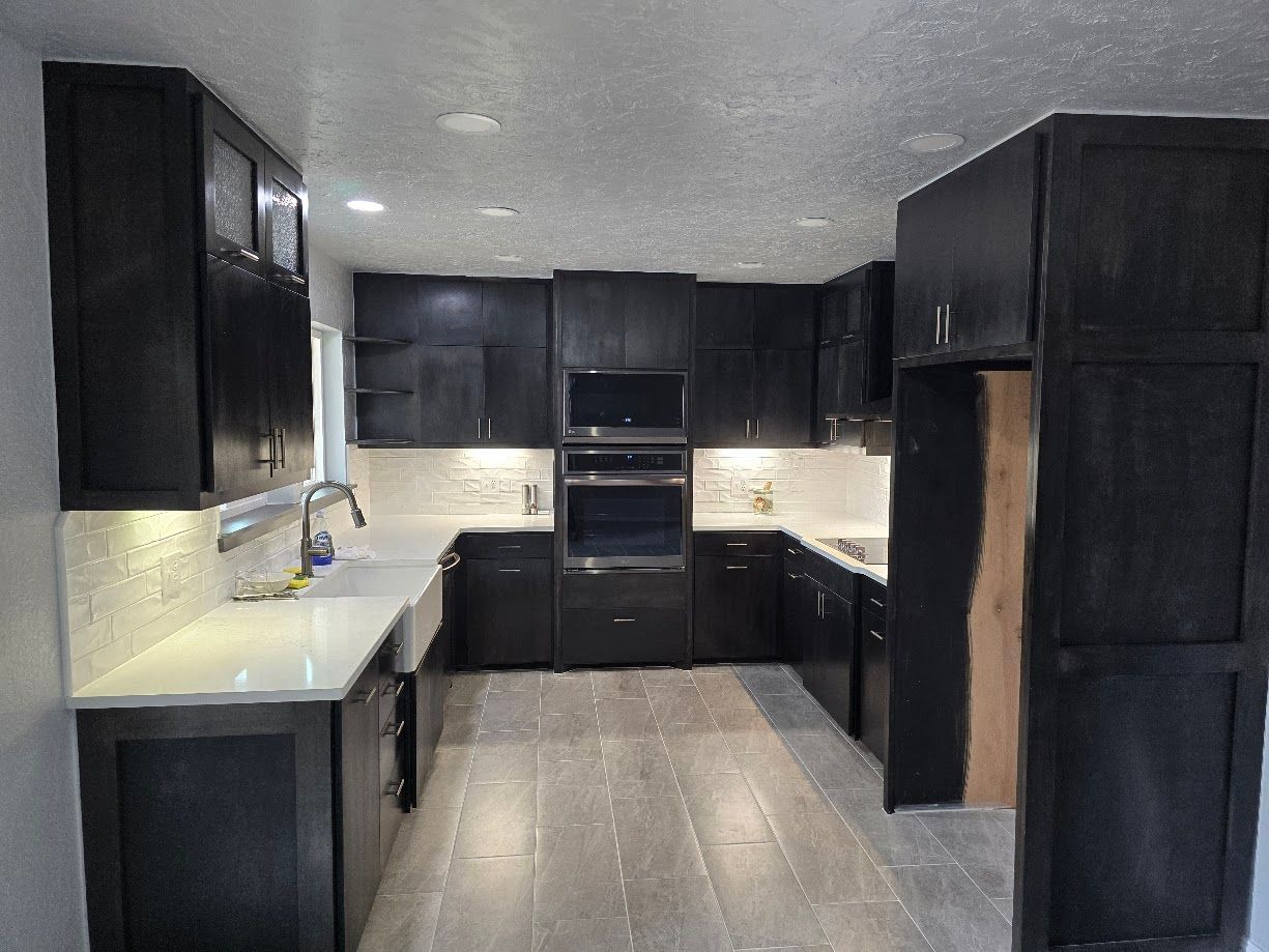 Modern kitchen with dark cabinets, light countertops, and stainless steel appliances, viewed from the entryway