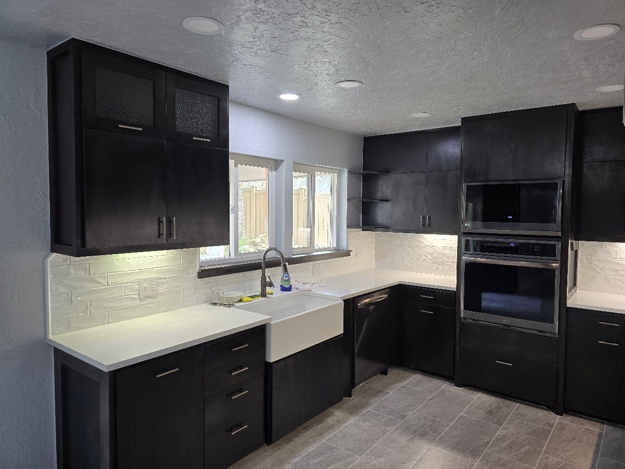 Modern black-and-white kitchen with white countertops, double sink, and built-in oven.