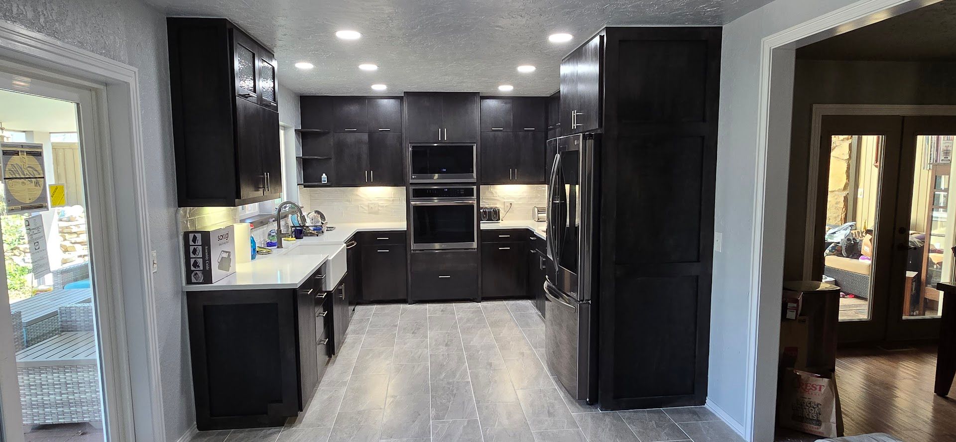 Modern kitchen with dark cabinets, stainless appliances, and gray tile flooring