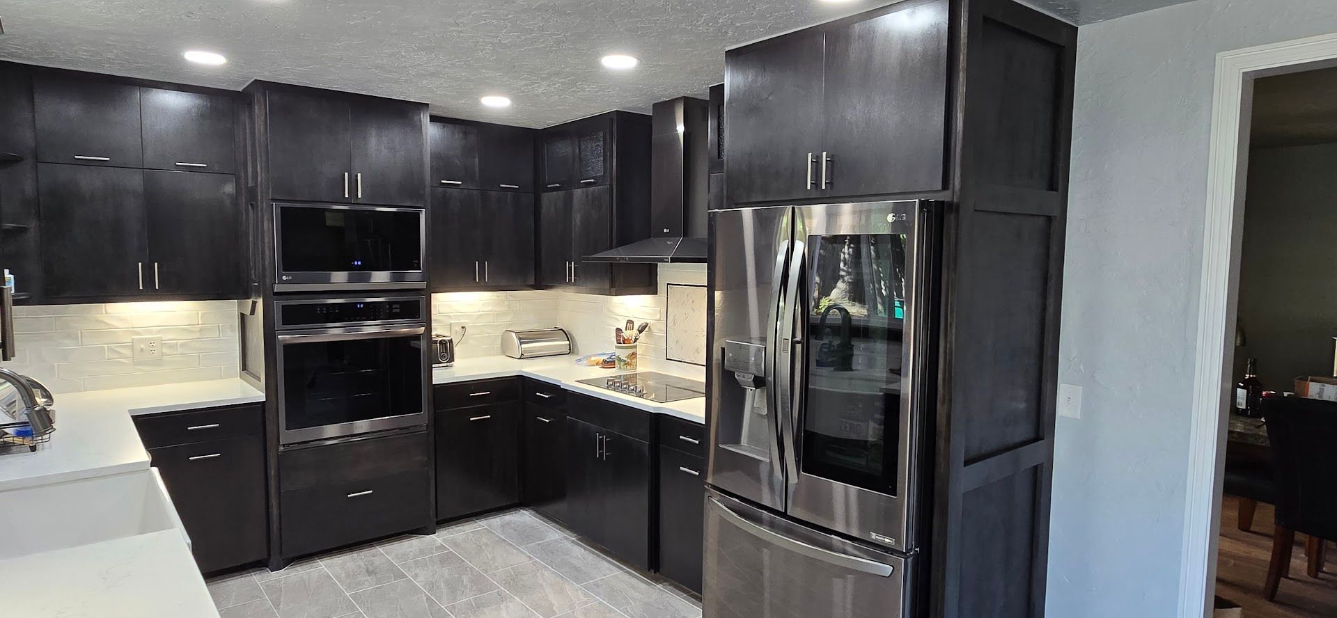 Modern dark-wood kitchen with stainless steel appliances and light countertops