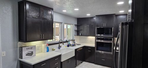 Modern black-and-white kitchen with stainless steel appliances and bright recessed lighting
