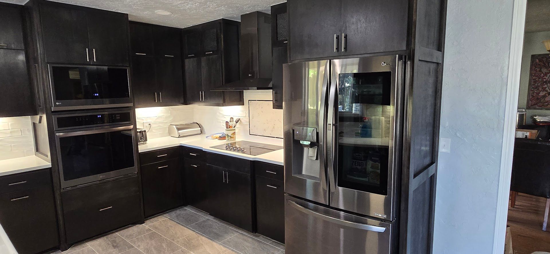 Modern kitchen with dark cabinets, stainless steel appliances, and gray tile flooring
