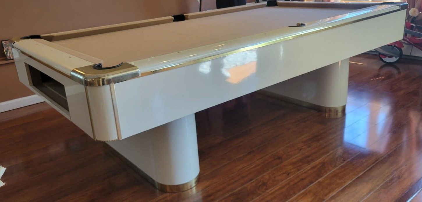 White pool table with tan pockets on a glossy wooden floor in a room