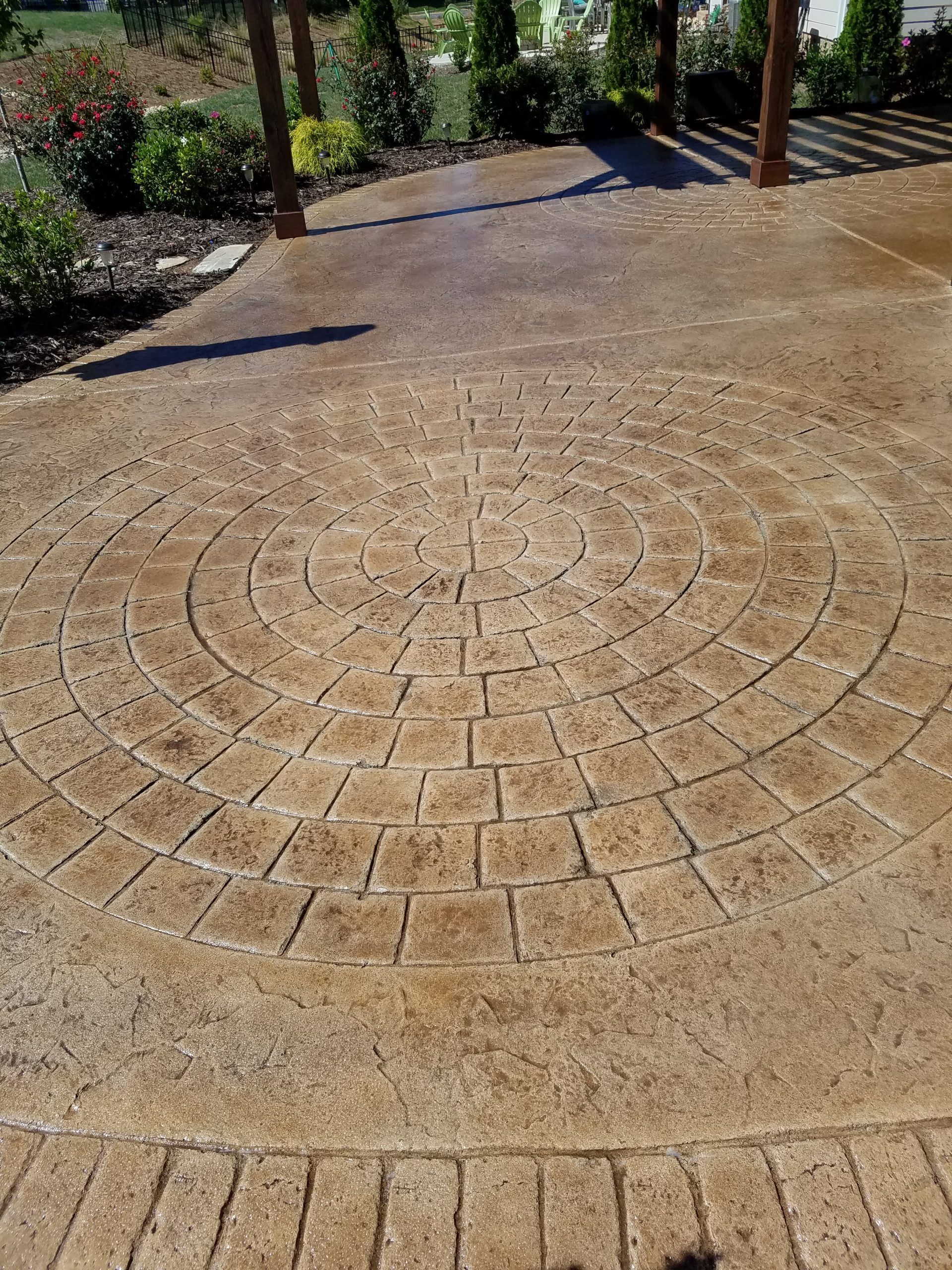 Outdoor brick patio with a circular decorative brick pattern and surrounding greenery