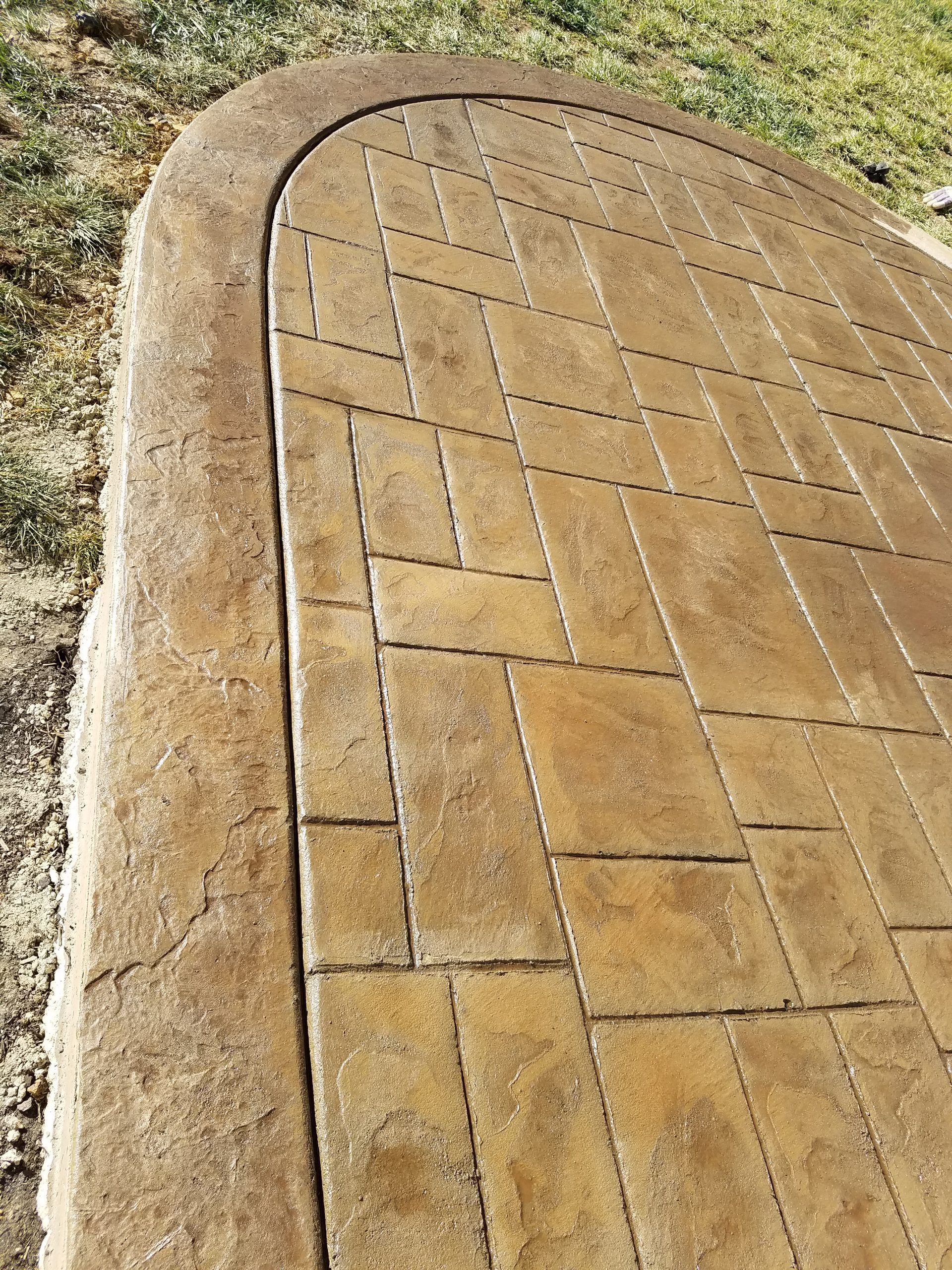 Curved stone pavement with a grid of rectangular bricks in tan and gray.