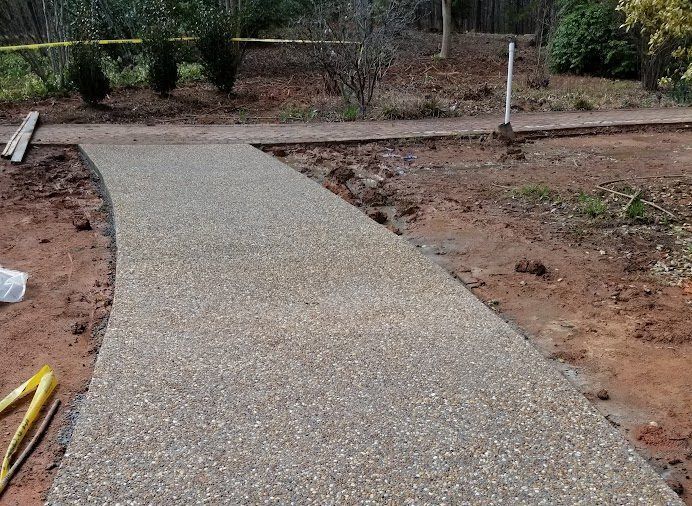 New gravel walkway leading to a dirt path in a landscaped outdoor area