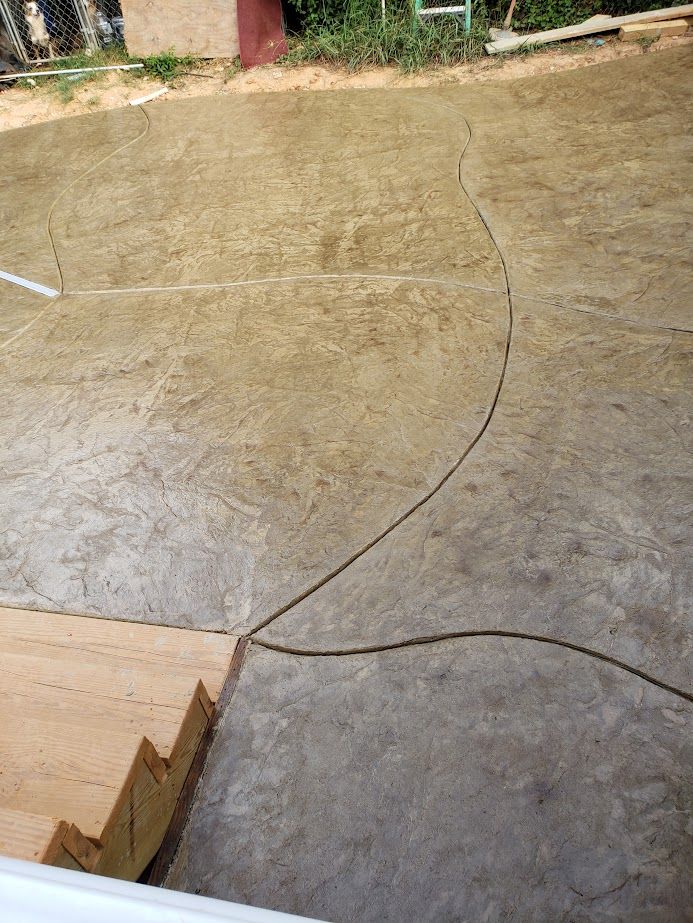 Concrete courtyard with a large curved crack and a wooden step in the lower left.