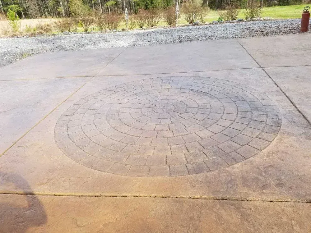 Concrete driveway with a circular brick inset pattern in the center.