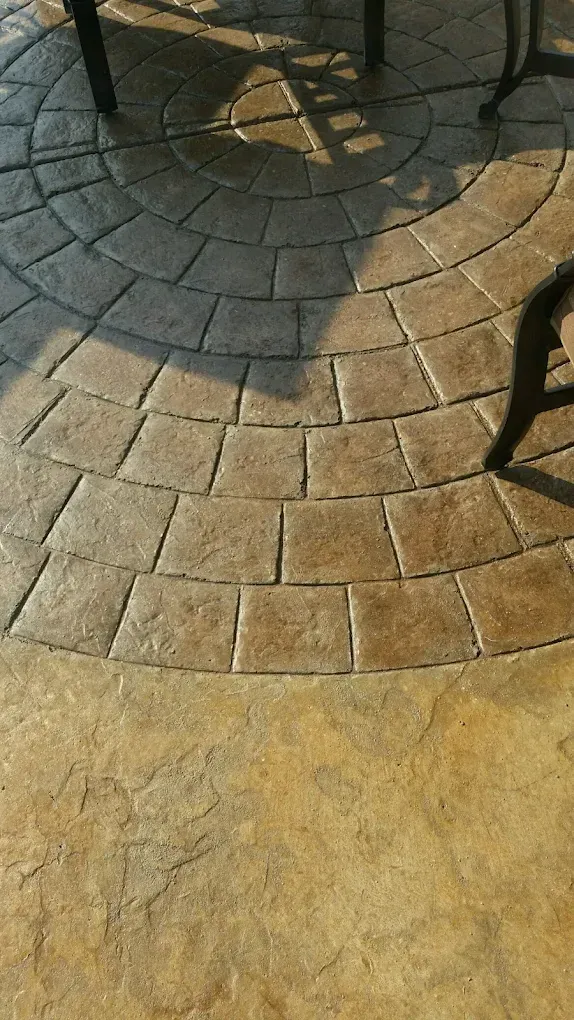 Paved stone patio with circular gray and tan brick pattern in sunlight