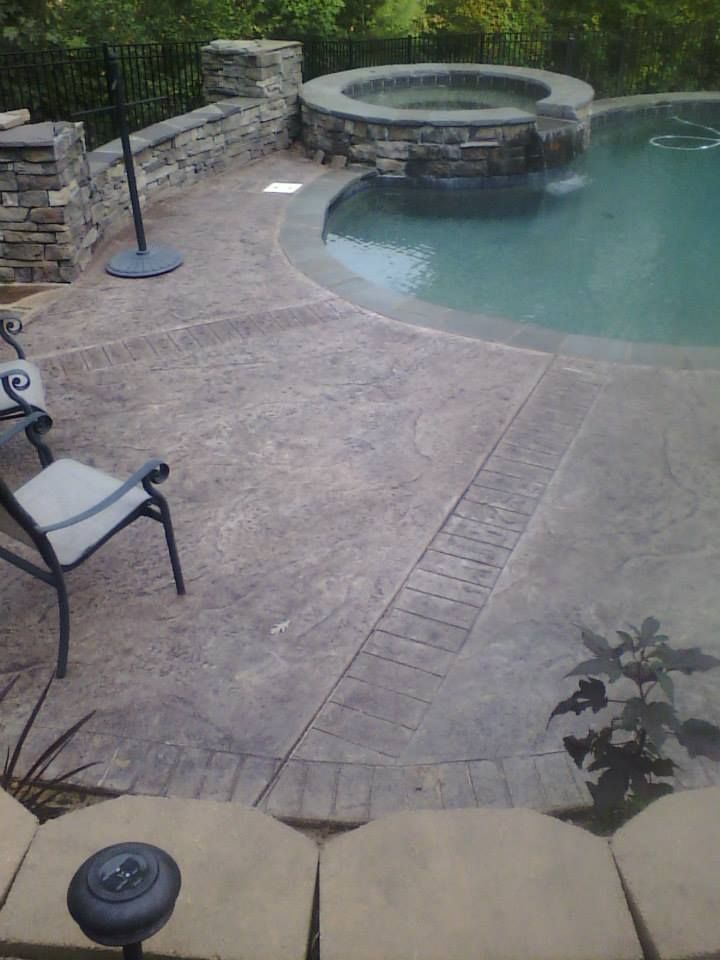 Backyard pool and spa with stone patio, chairs, and a small waterfall feature