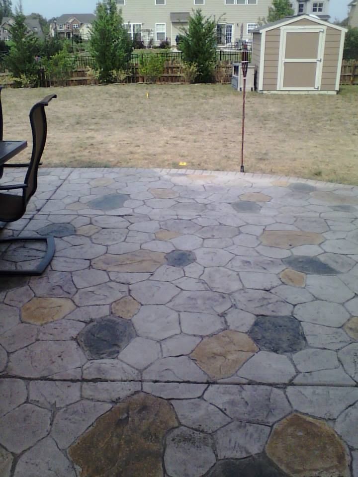 Stone patio overlooking a dry backyard with a shed and neighboring houses in the distance
