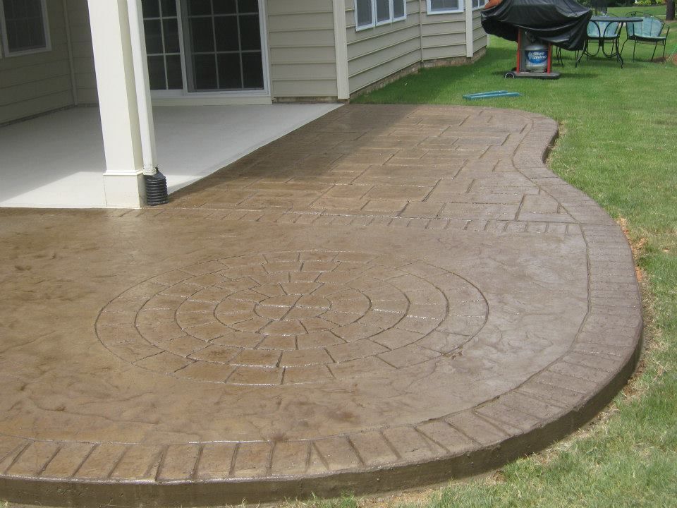 Stamped concrete patio beside a house, curving around a grassy yard.