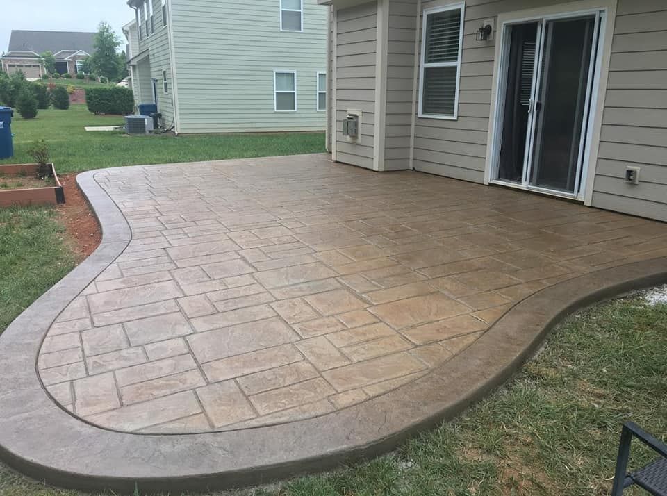Stamped concrete patio beside a house with curved edging and sliding glass doors