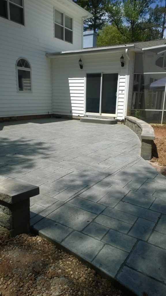 House exterior with a curved stone patio and a small white shed by the wall