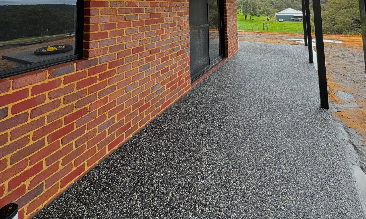Redbrick building walkway with black posts and wet gray gravel ground after rain