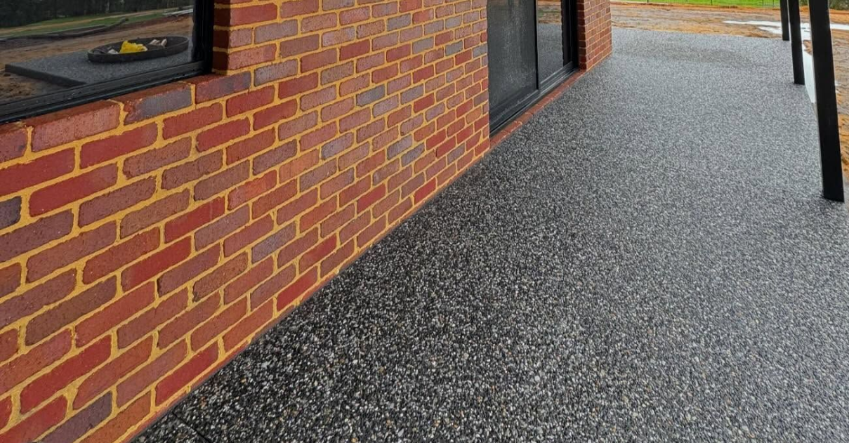 Black exposed aggregate wrap around alfresco contrasted with red brick house. 