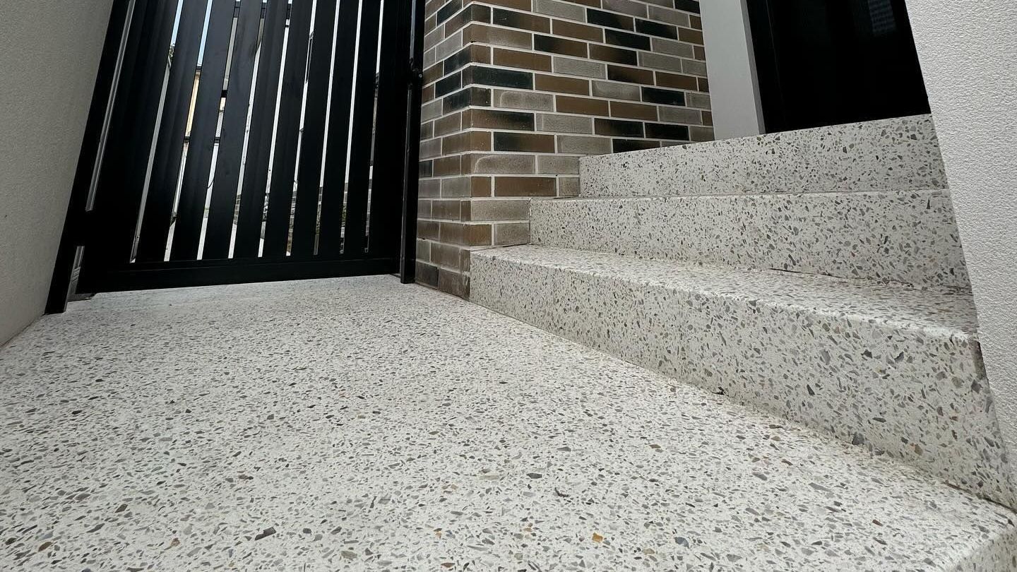 Amber white mix for a honed concrete entrance with stairs to a three story home. Complimented with black gate,