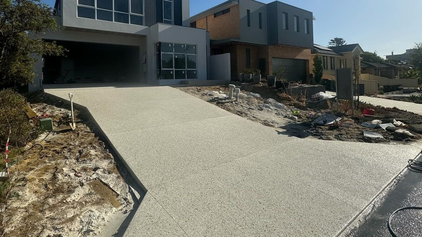 An exposed aggregate driveway leading to a house with solar panels on the roof