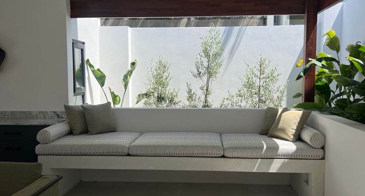 Architectural concrete bench seat and day bed with cushions under open air patio.