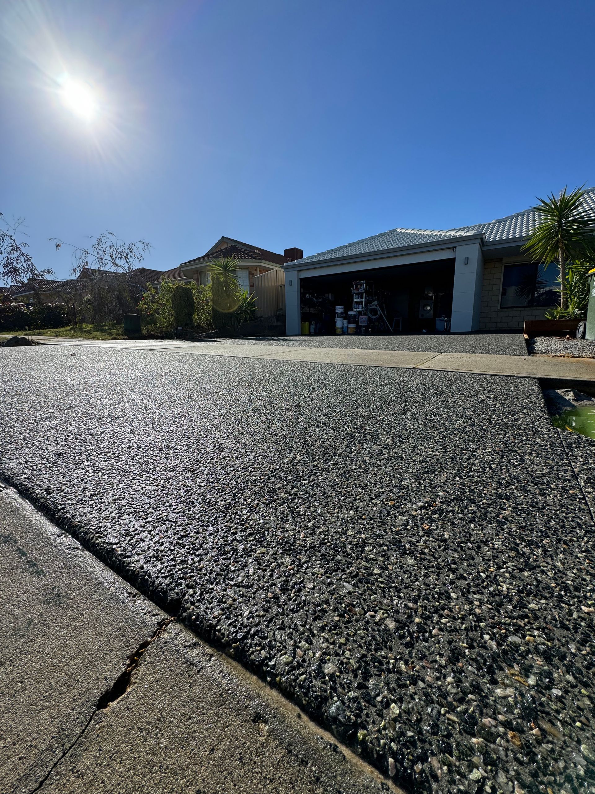 Close up of charcoal exposed aggregate driveway with crossover.