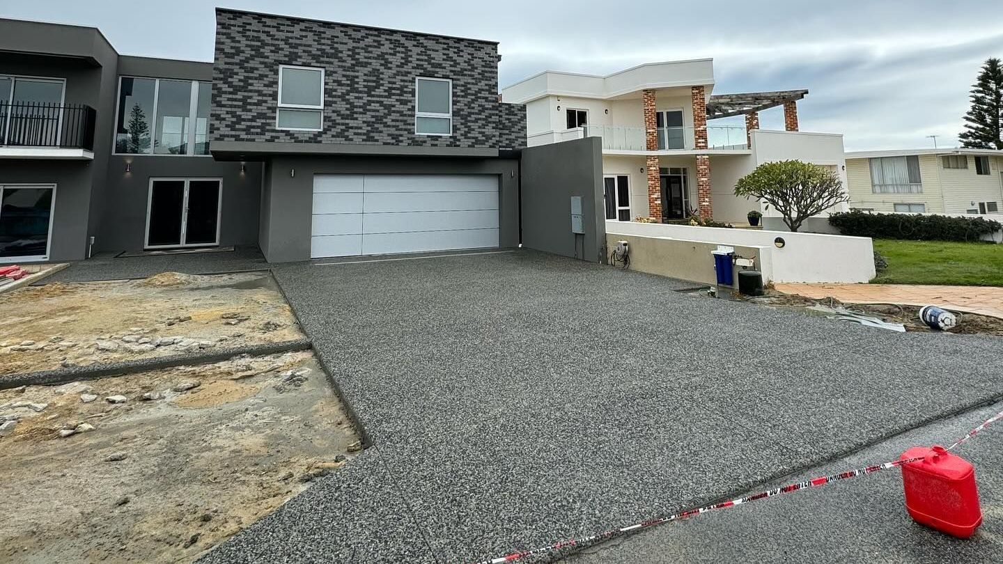 A large house with a new exposed aggregate driveway in front of it.