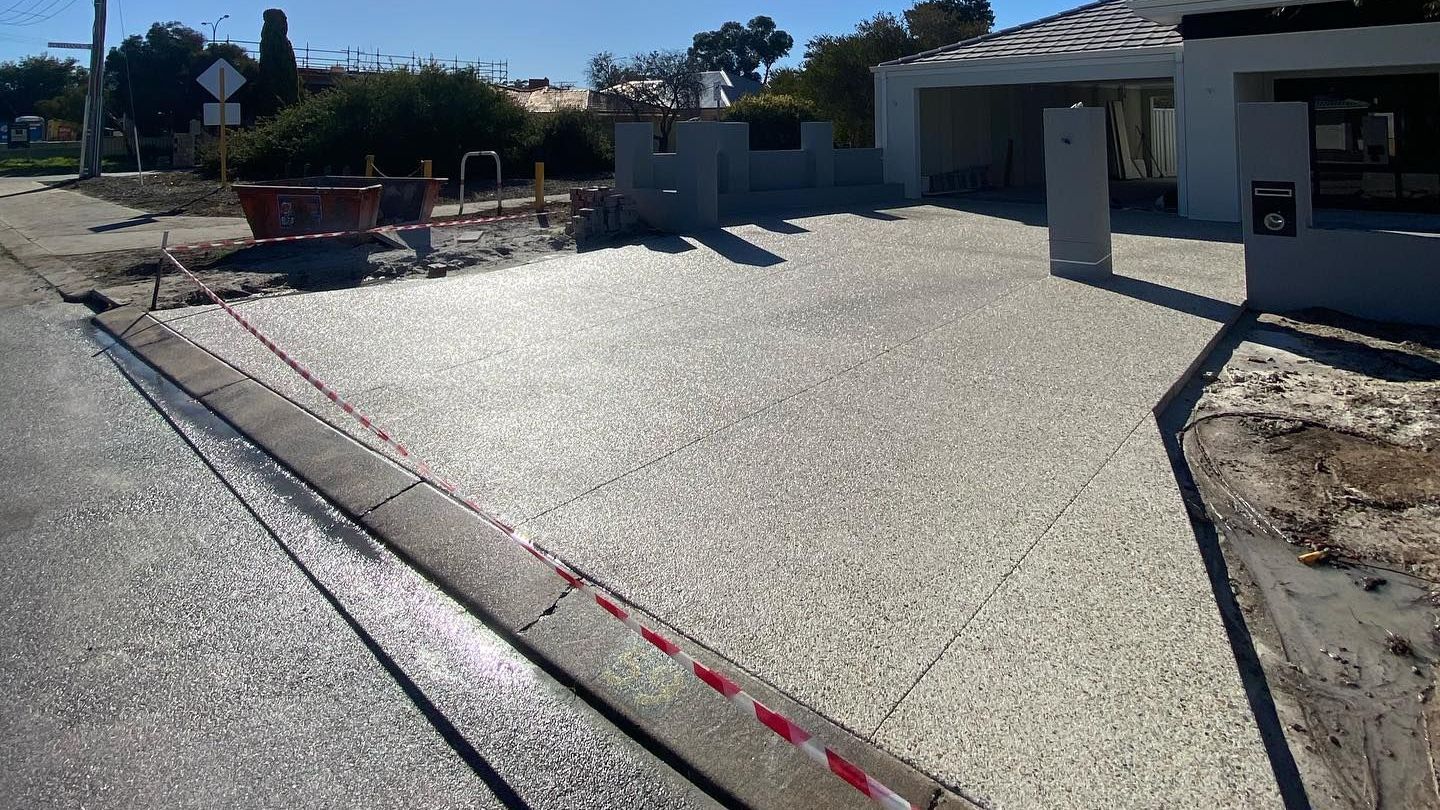 Freshly poured concrete driveway under construction. Red and white tape blocks entry.