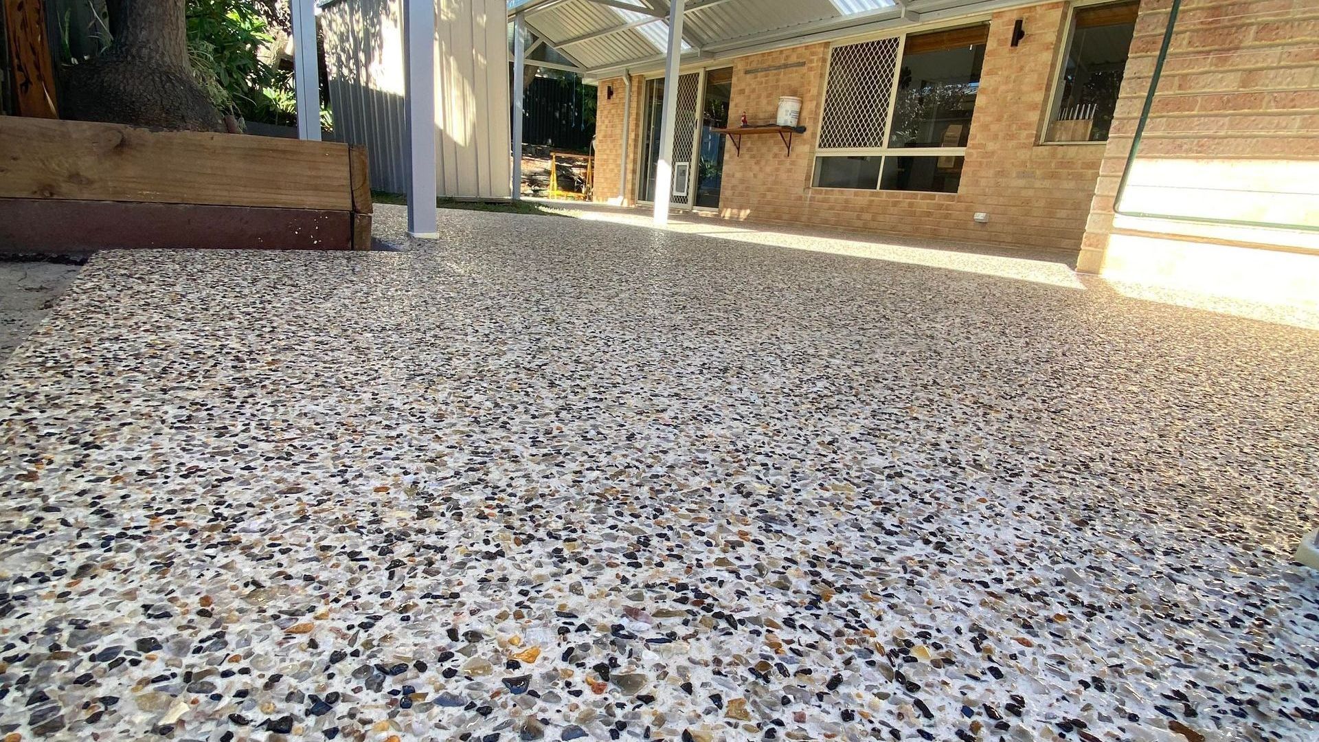 Concrete patio with exposed aggregate in front of a brick home