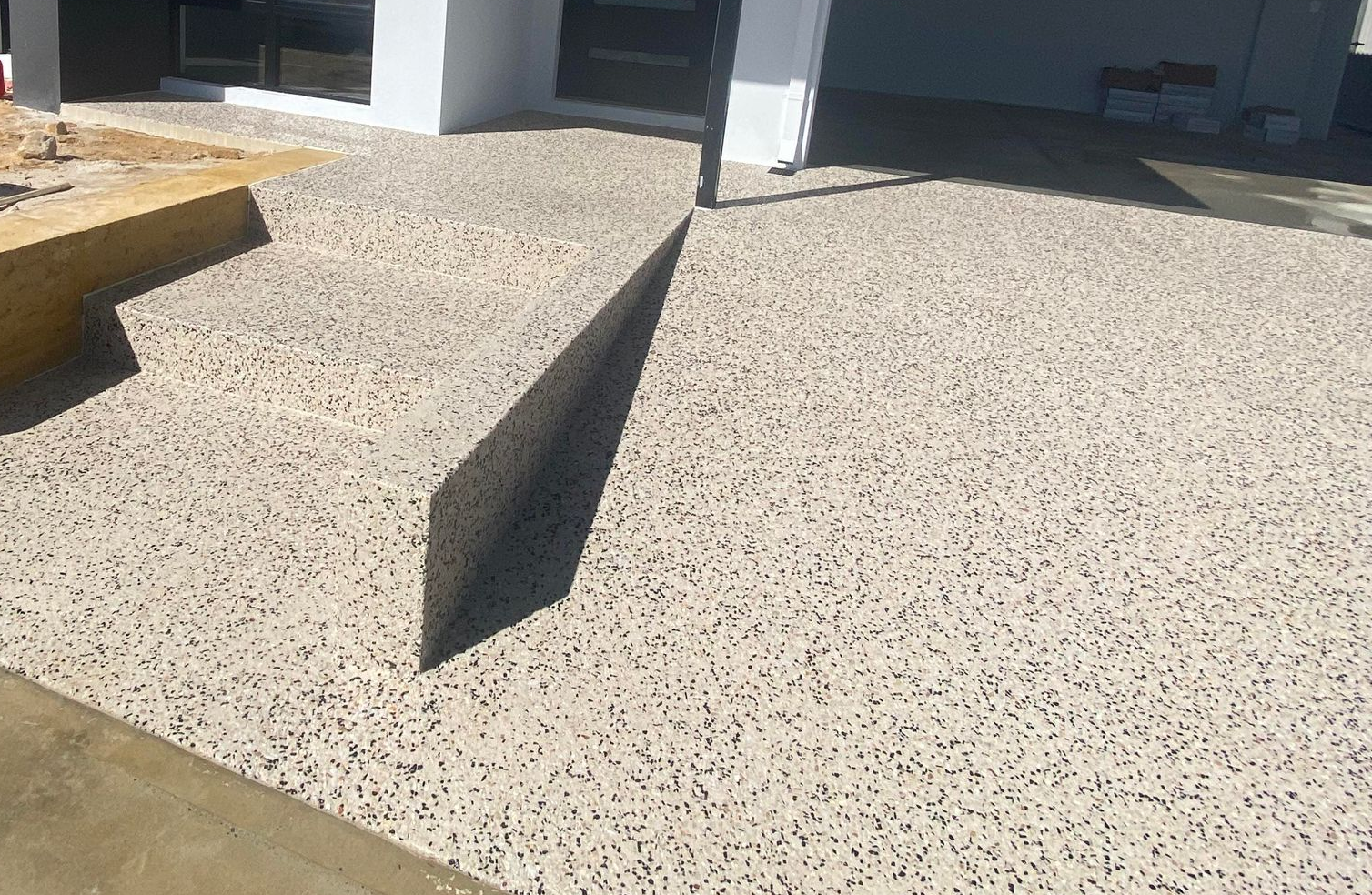 Exposed aggregate stairs and matching driveway leading to house entrance and front door.