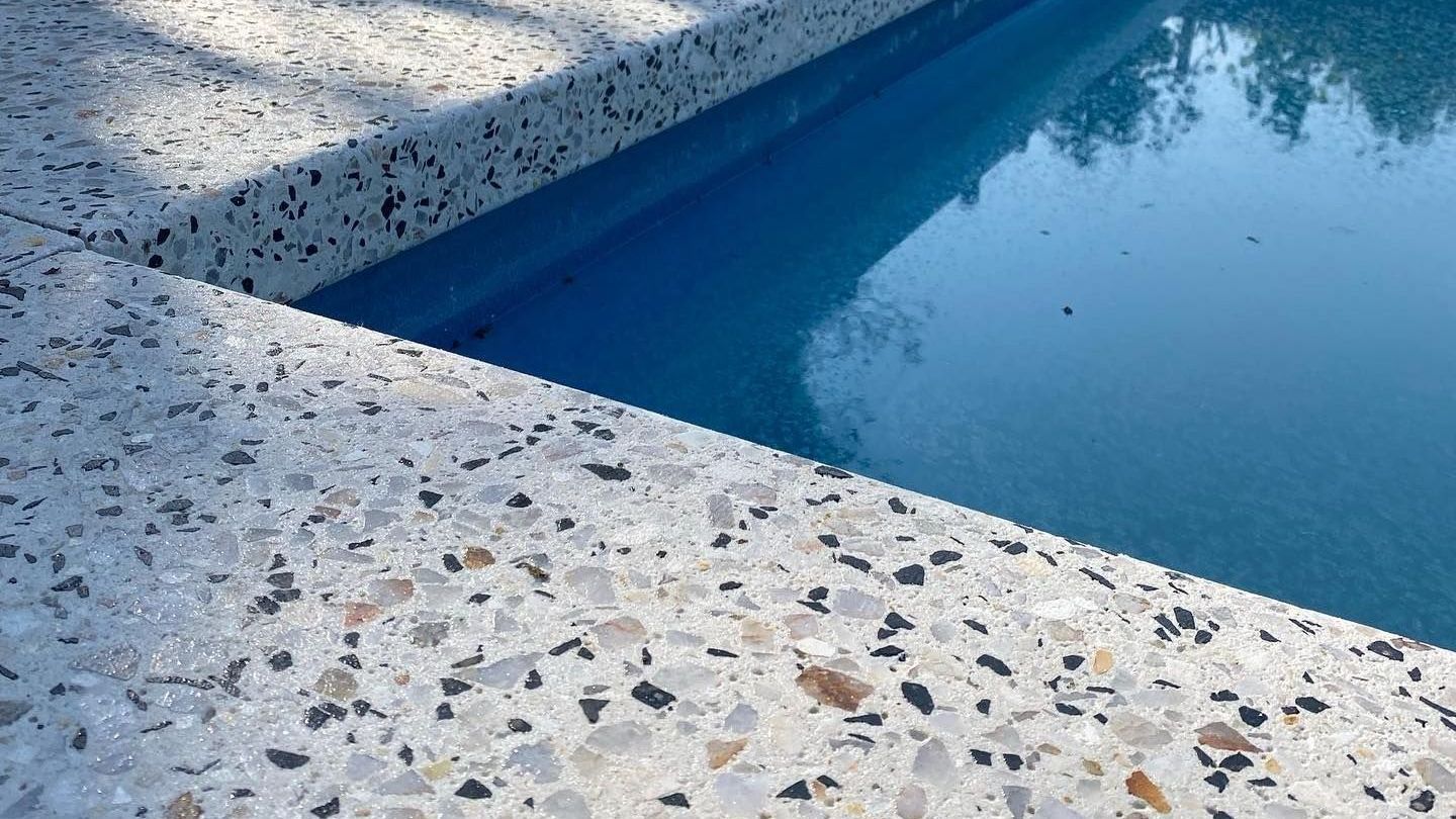 Honed light concrete pool surrounds with speckled effect throughout.