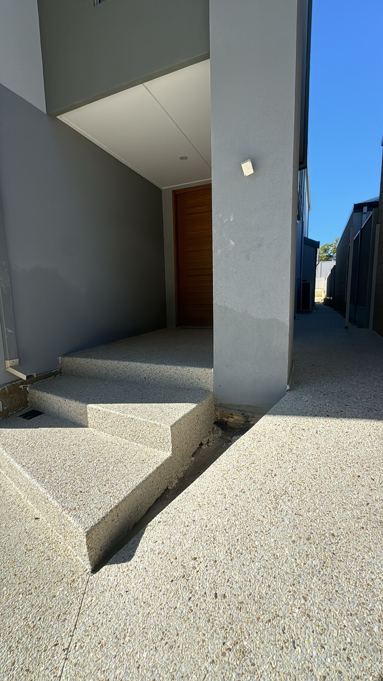 Exposed aggregate concrete house entrance with stairs leading to the front door.