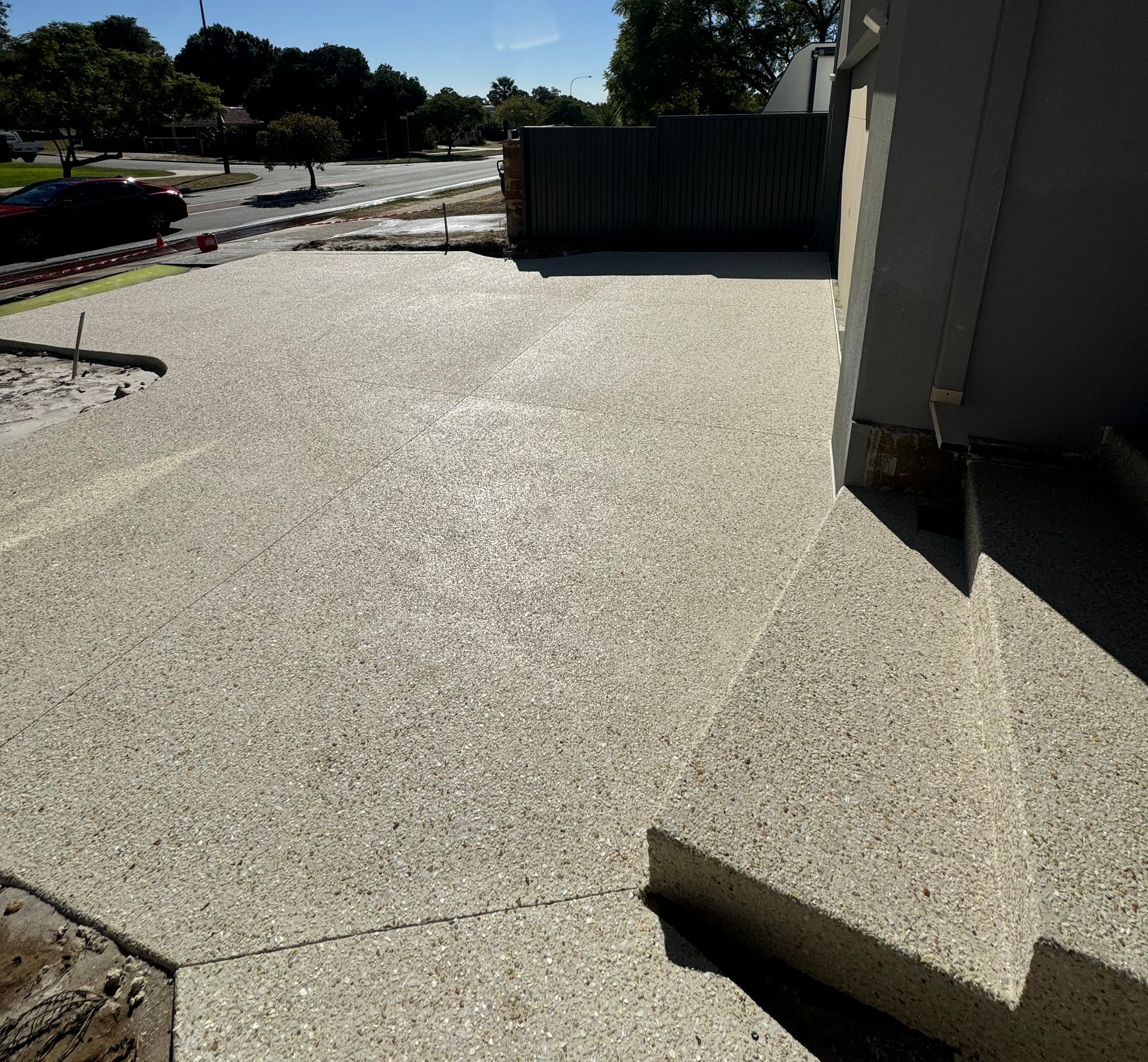 Exposed aggregate concrete driveway and steps outside a house.