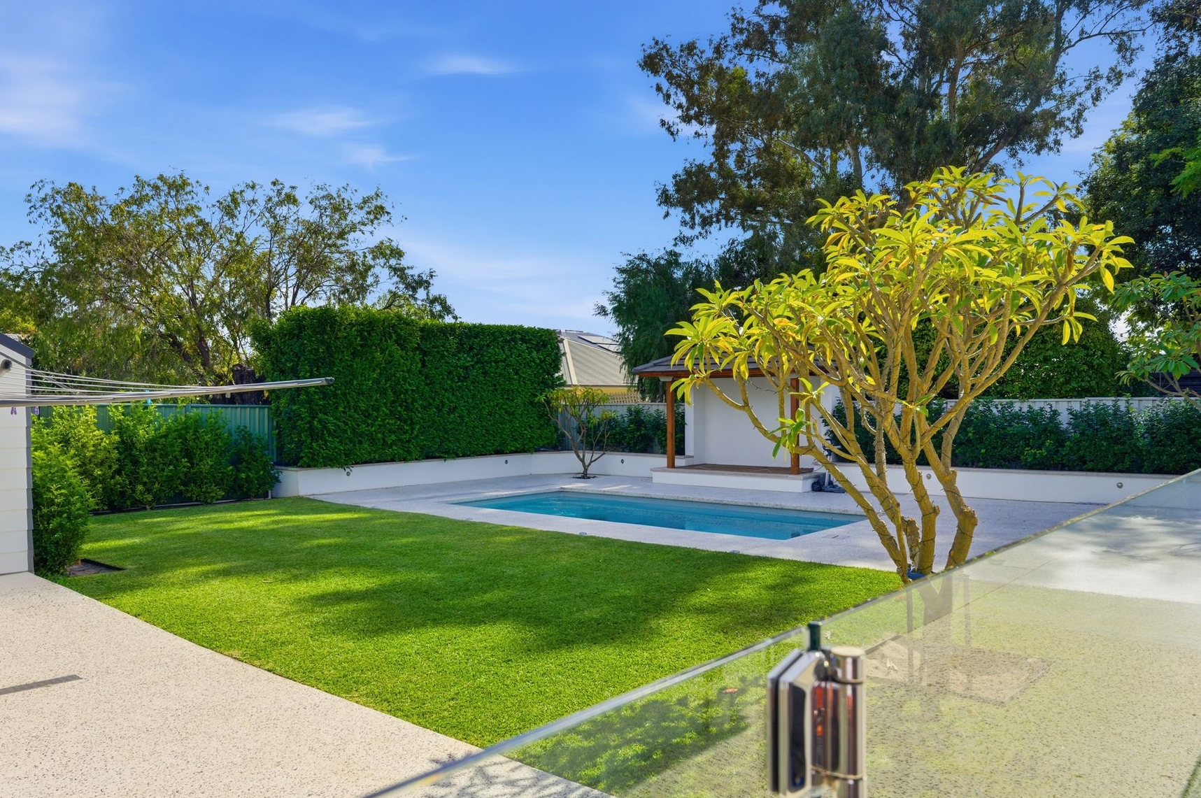 Exposed aggregate pool surrounds with landscaped backyard.