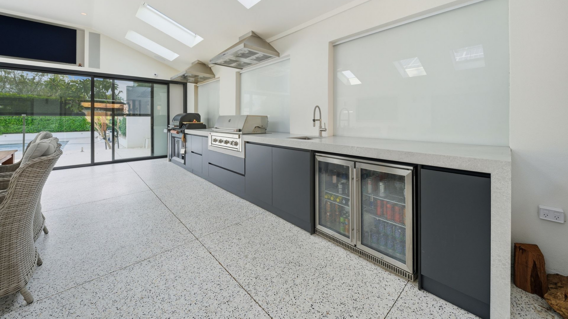 Modern kitchen with exposed aggregate flooring and bifold glass doors.