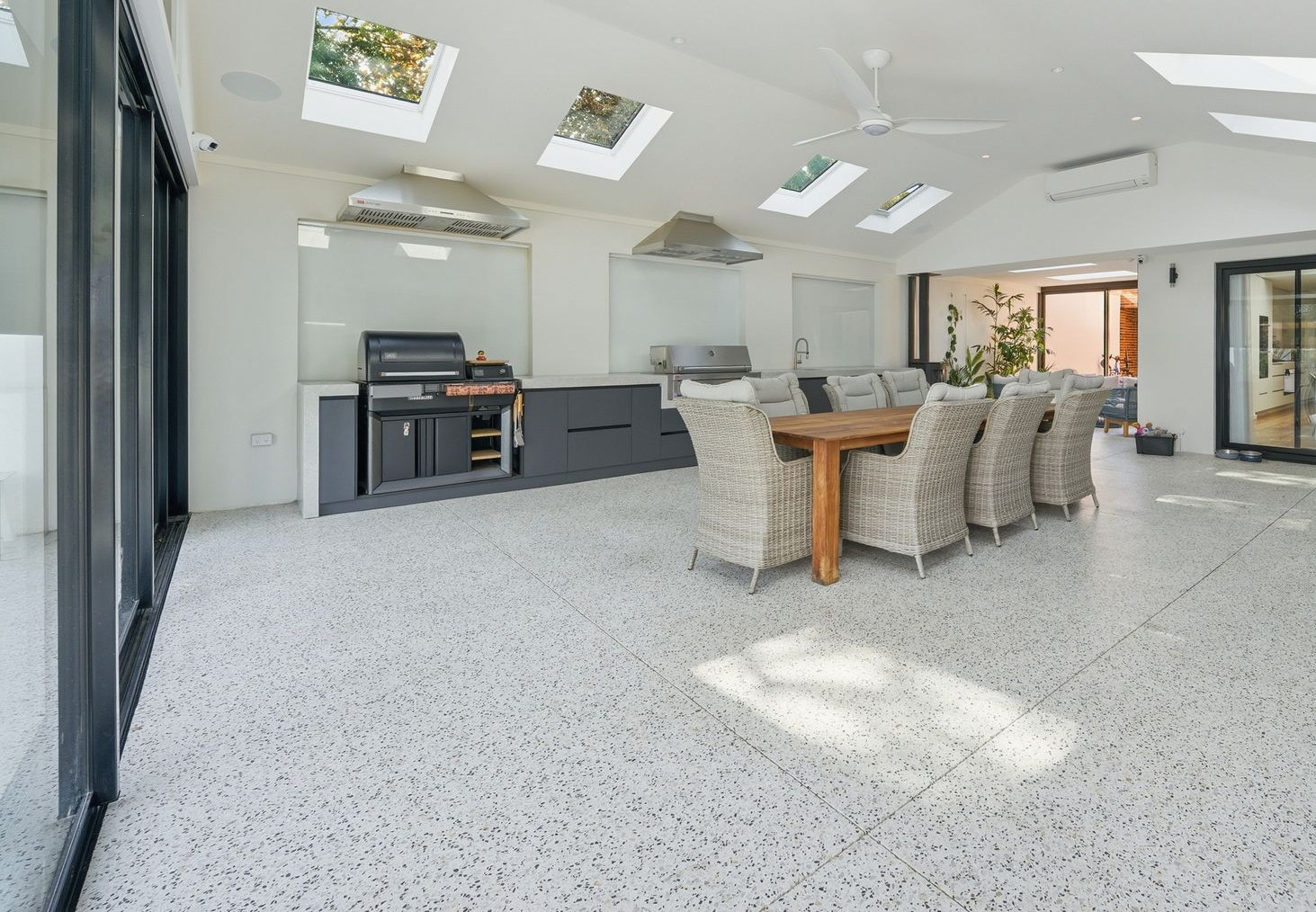 Bright modern patio with exposed aggregate flooring, skylights and outdoor kitchen.