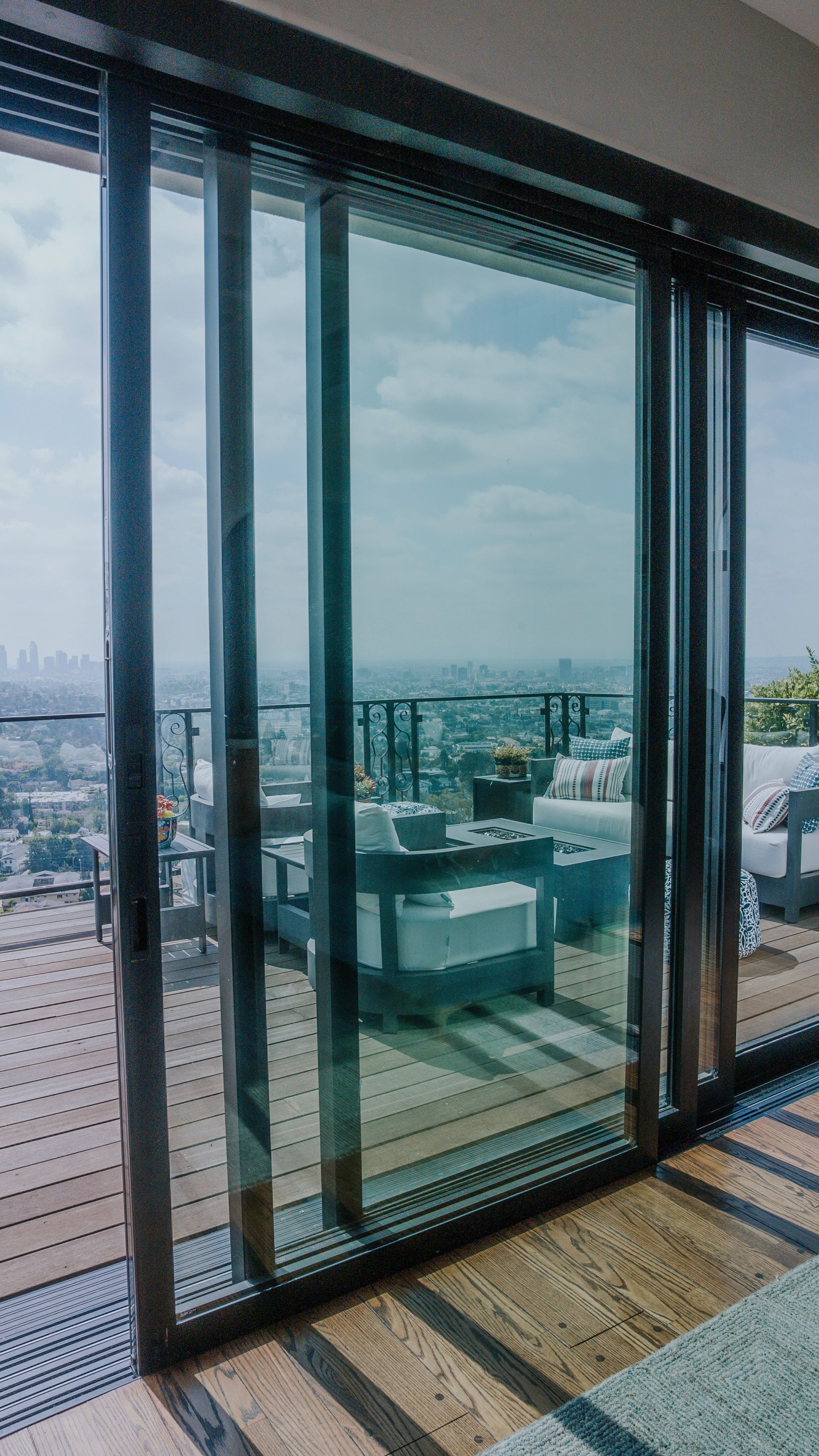 Sliding glass door with a city view, opening onto a rooftop patio with furniture.