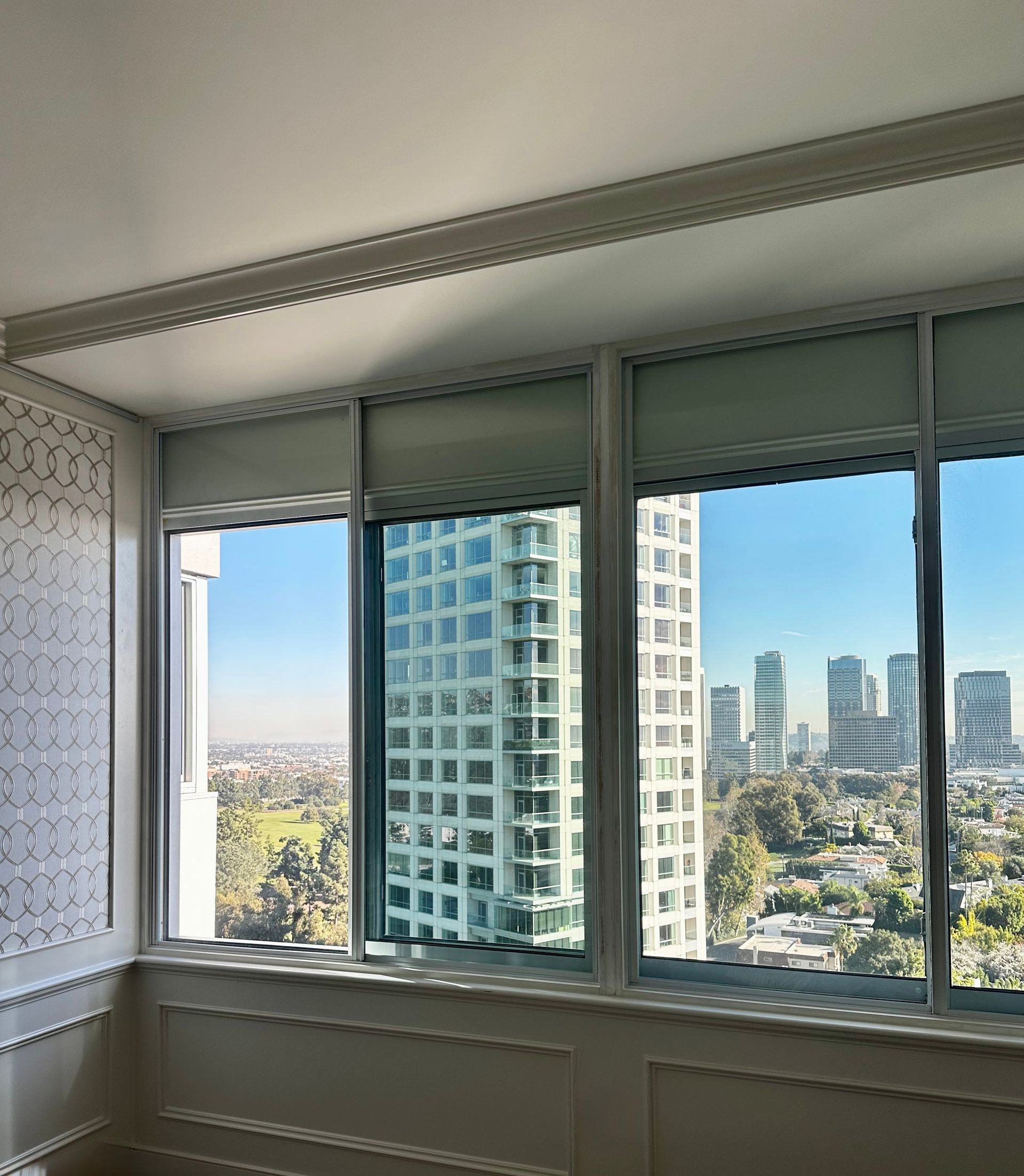 A high-rise window offering a city view, framed by white molding.