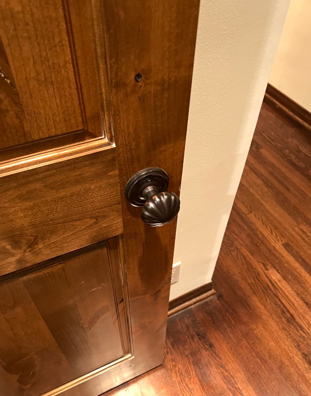 Wooden door with dark bronze doorknob and glossy finish.