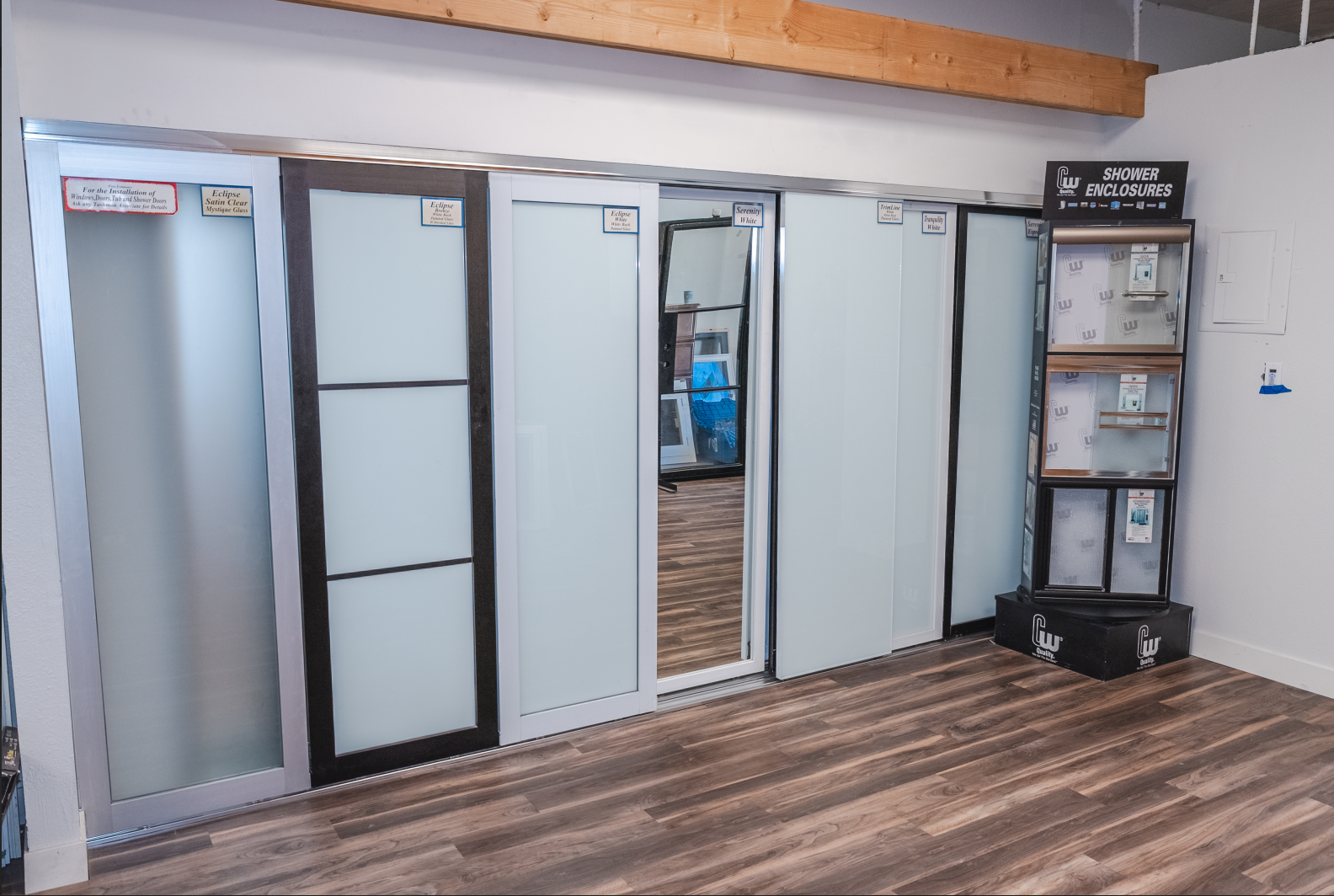 Mirrored sliding closet doors with dark frames, reflecting a room with tile flooring and a white door.