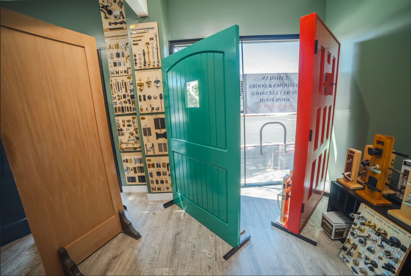 A showroom featuring doors of various colors, including green, red, and wooden, plus keys and door hardware.