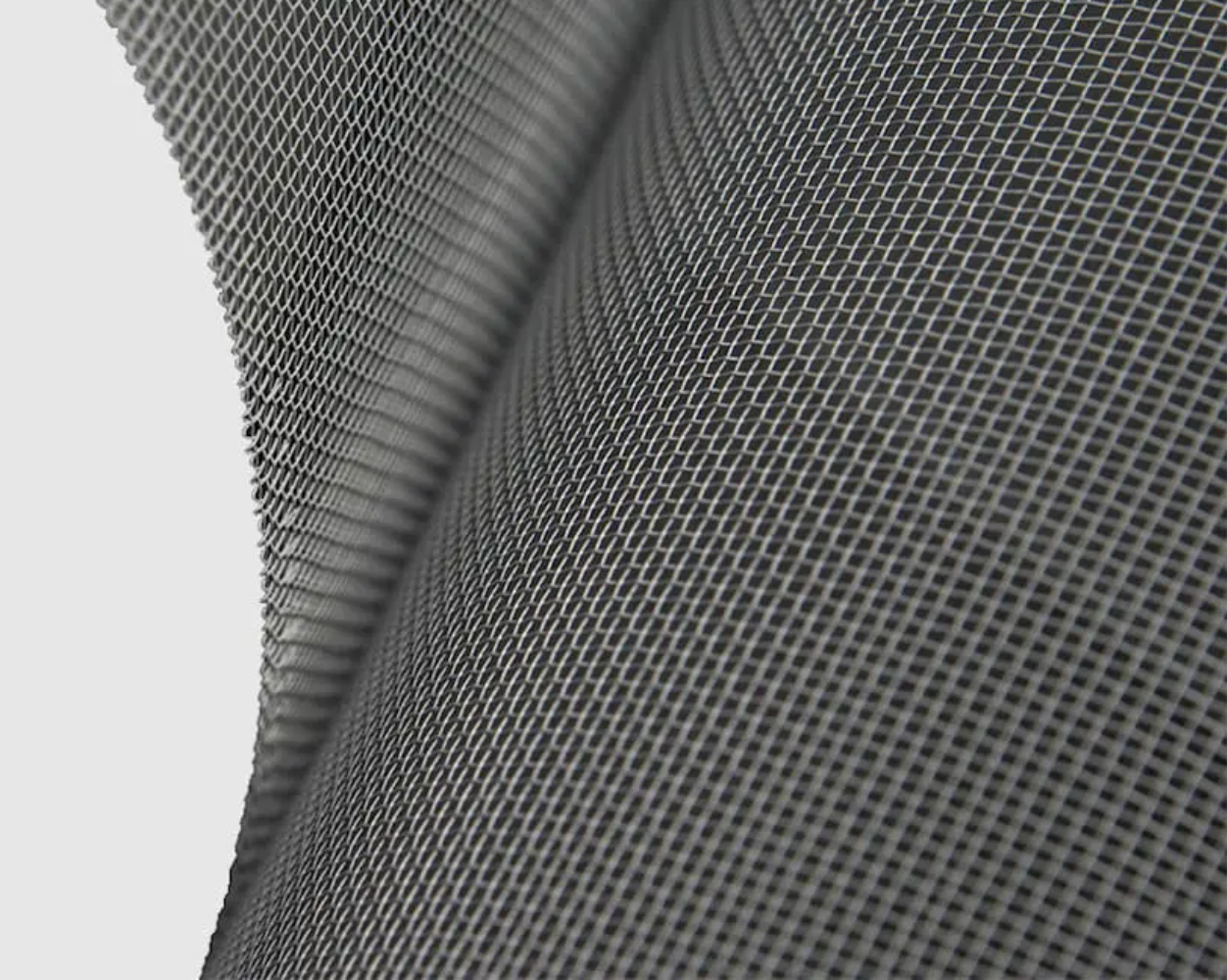 Close-up of a gray mesh material, with a curved edge and small, evenly spaced holes.