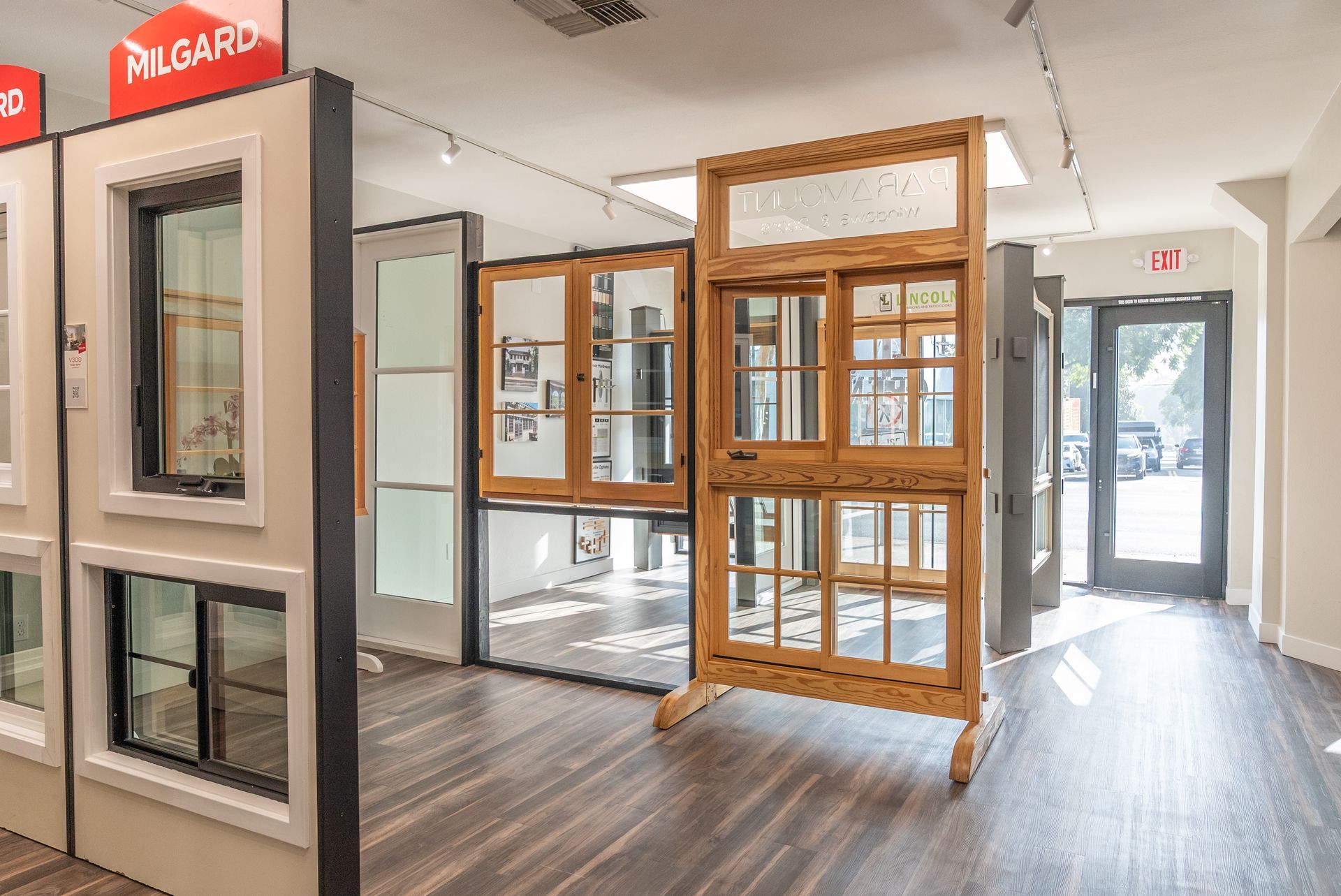 Window showroom with various window styles on display. Wooden frames, glass panels, neutral walls.
