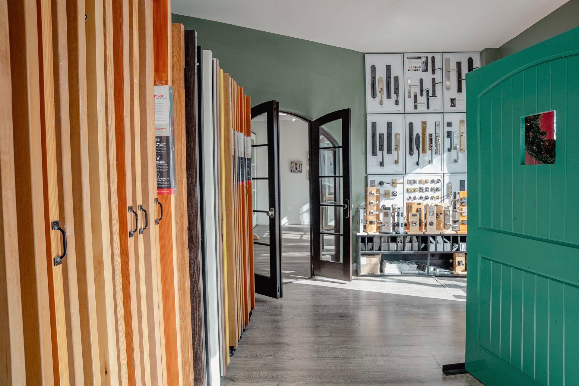 Wood samples displayed in a showroom with open doors and a teal door.