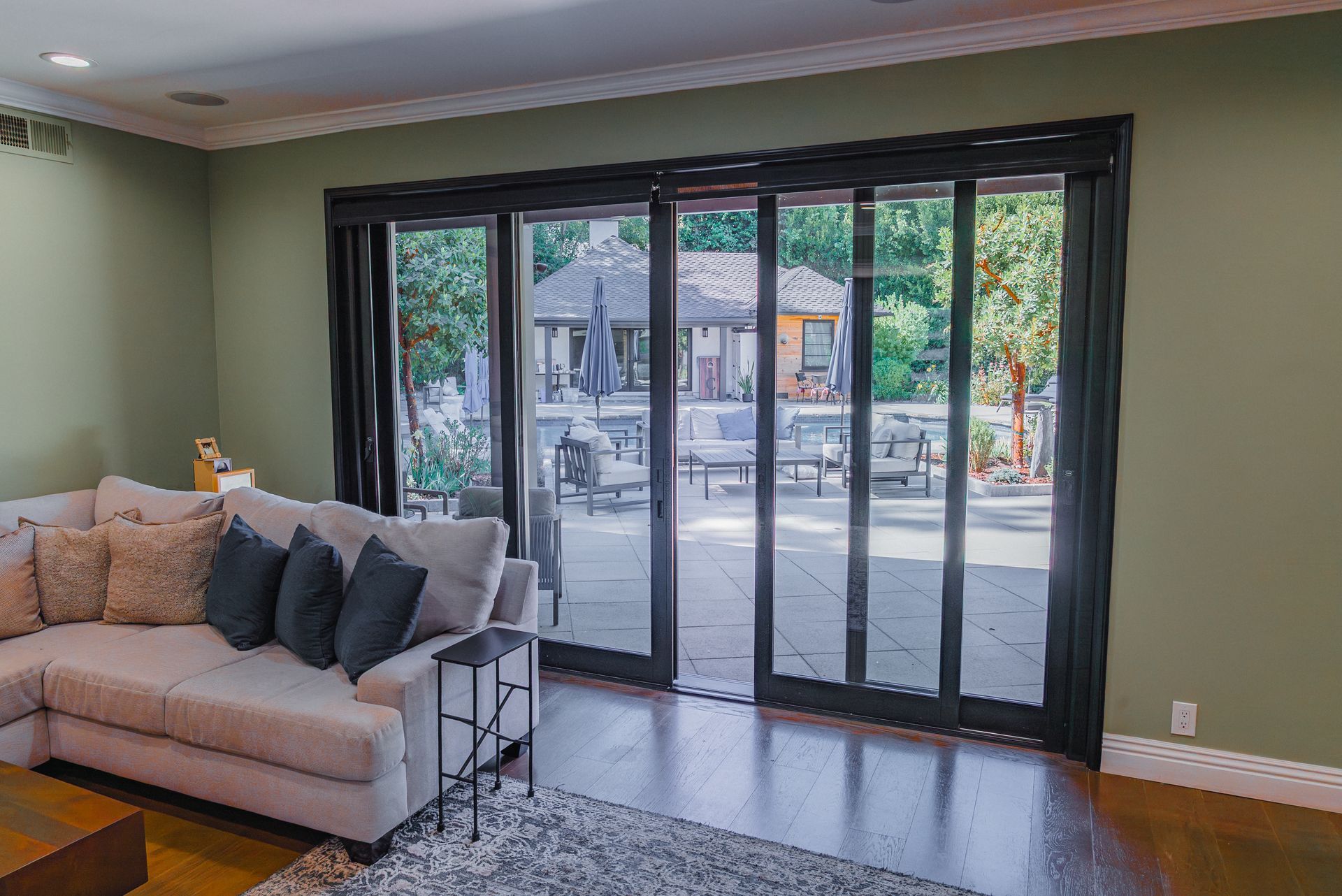 Living room with a sectional sofa, a black-framed sliding glass door opens to a patio with a gazebo.