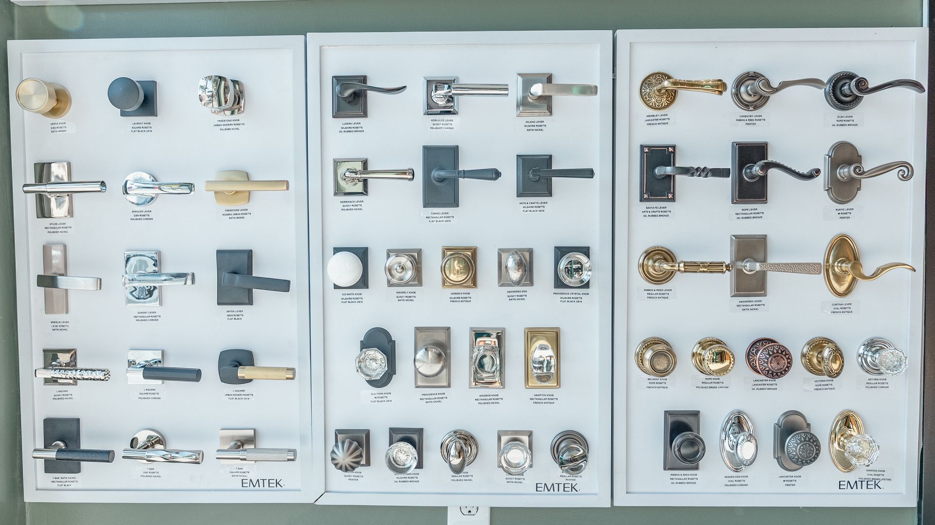 Door hardware display with various knobs and levers in silver, black, and gold tones.