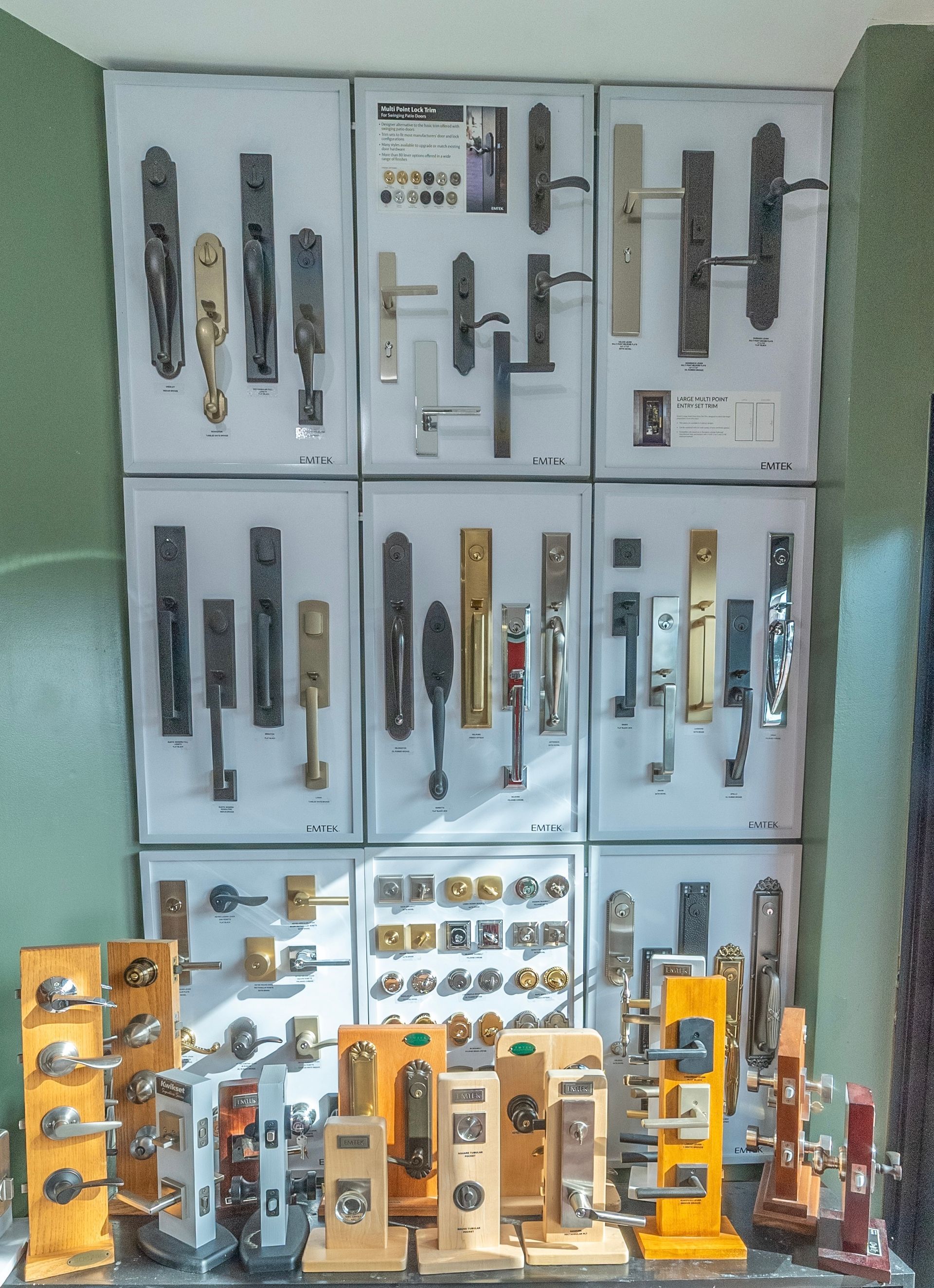 Display of various door handles and hardware, arranged on white panels and stands, in a store setting.