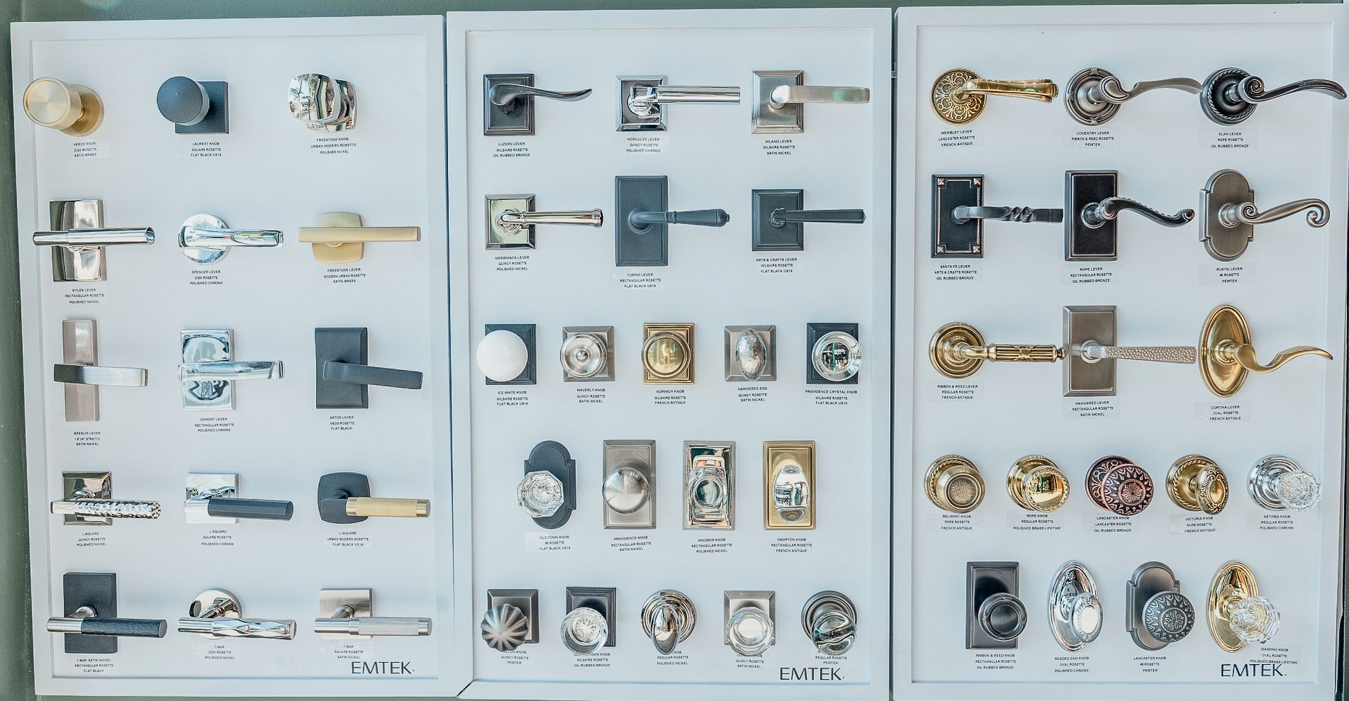 Door hardware display with various knobs, levers, and escutcheons in silver, black, and gold tones.